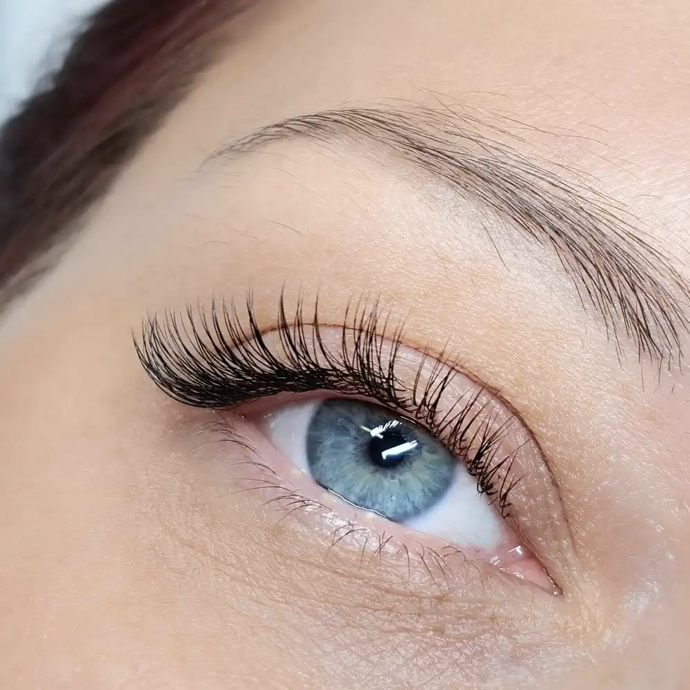 Close-up of a blue eye with natural classic eyelash extensions, enhancing length and definition.